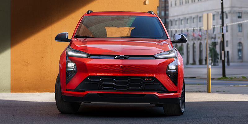Front view of a red Chevrolet Blazer EV in a city setting, with large grilles and sleek headlights.