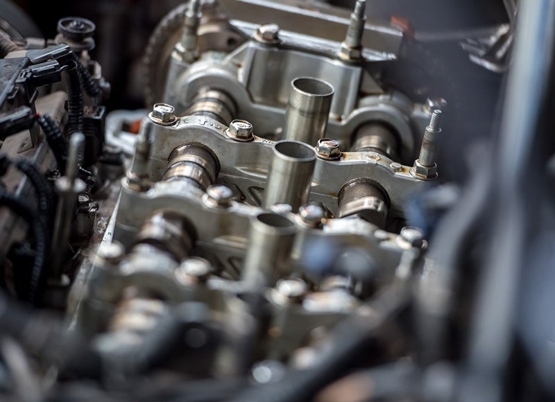 Close-up of a disassembled internal combustion engine, showing camshafts, bolts, and metal components.