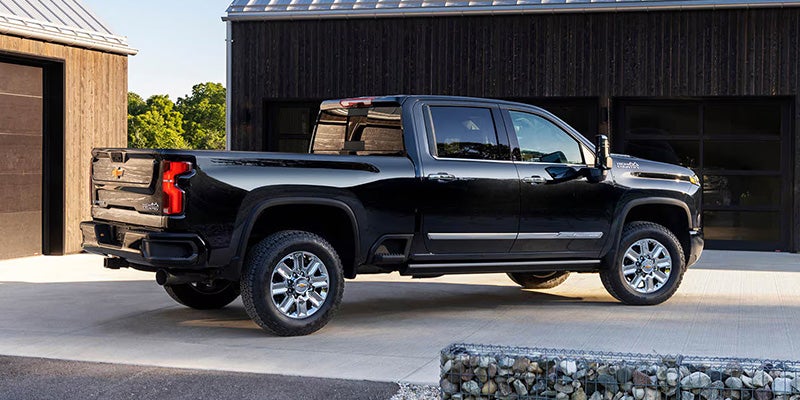 Black Chevrolet Silverado pickup truck parked outside a modern garage with a sleek exterior design.