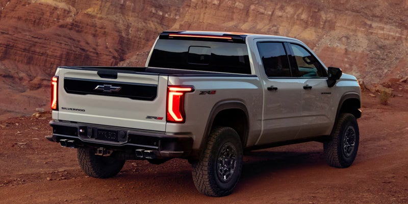 Chevrolet Silverado pickup truck parked on a rugged desert landscape with rocky canyon scenery.
